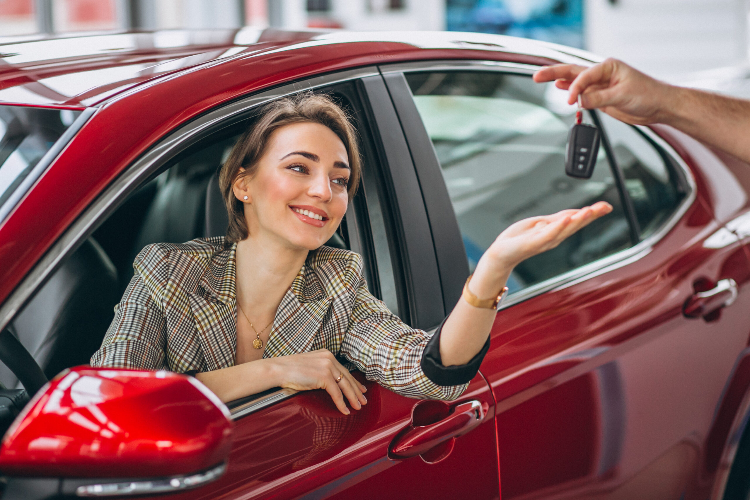 woman sitting red car receiving keys scaled